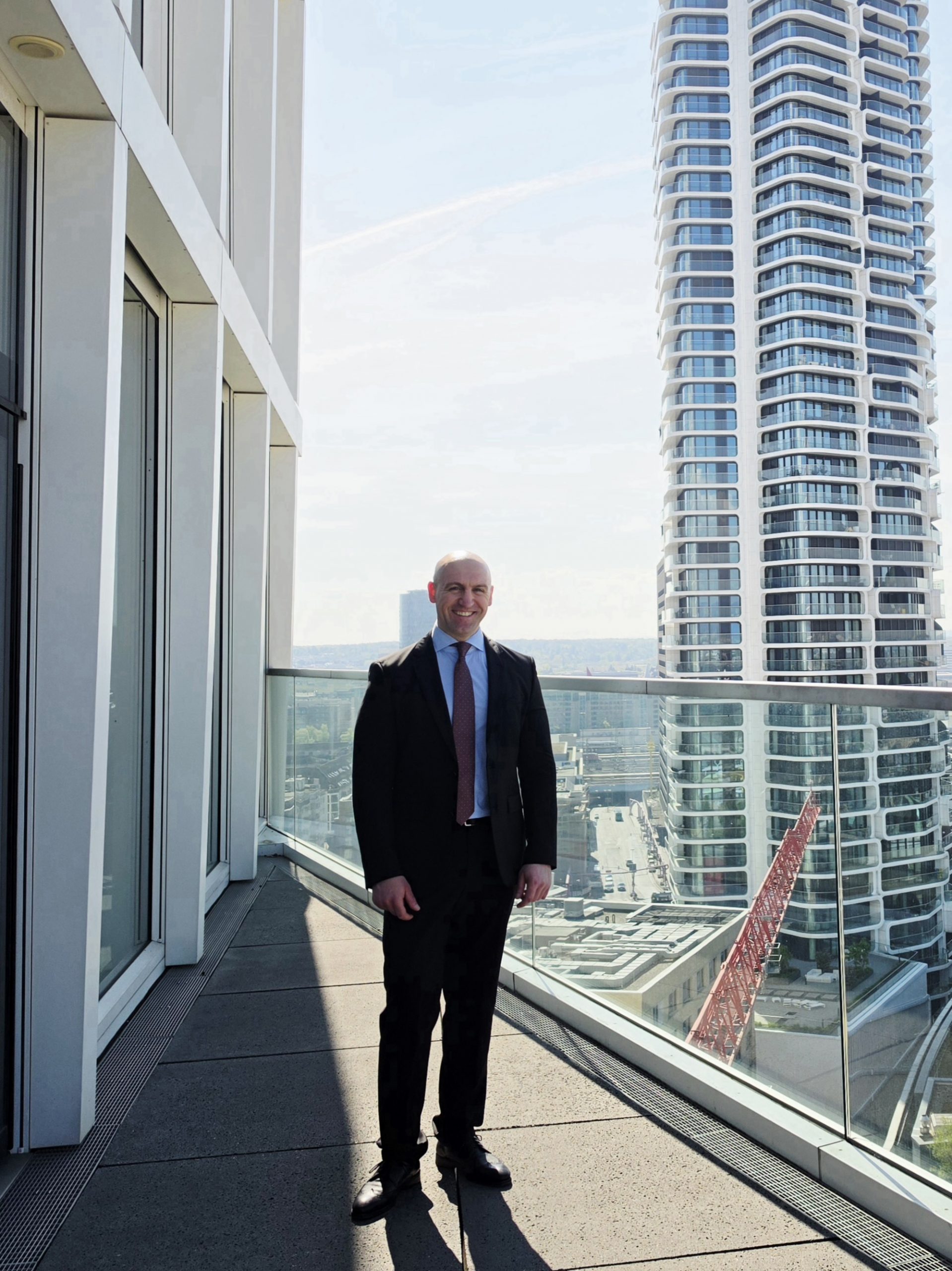 Ronny Kazyska vor moderner Architektur zum Grundsatz Zeitverzögerung im Immobilienmarkt.