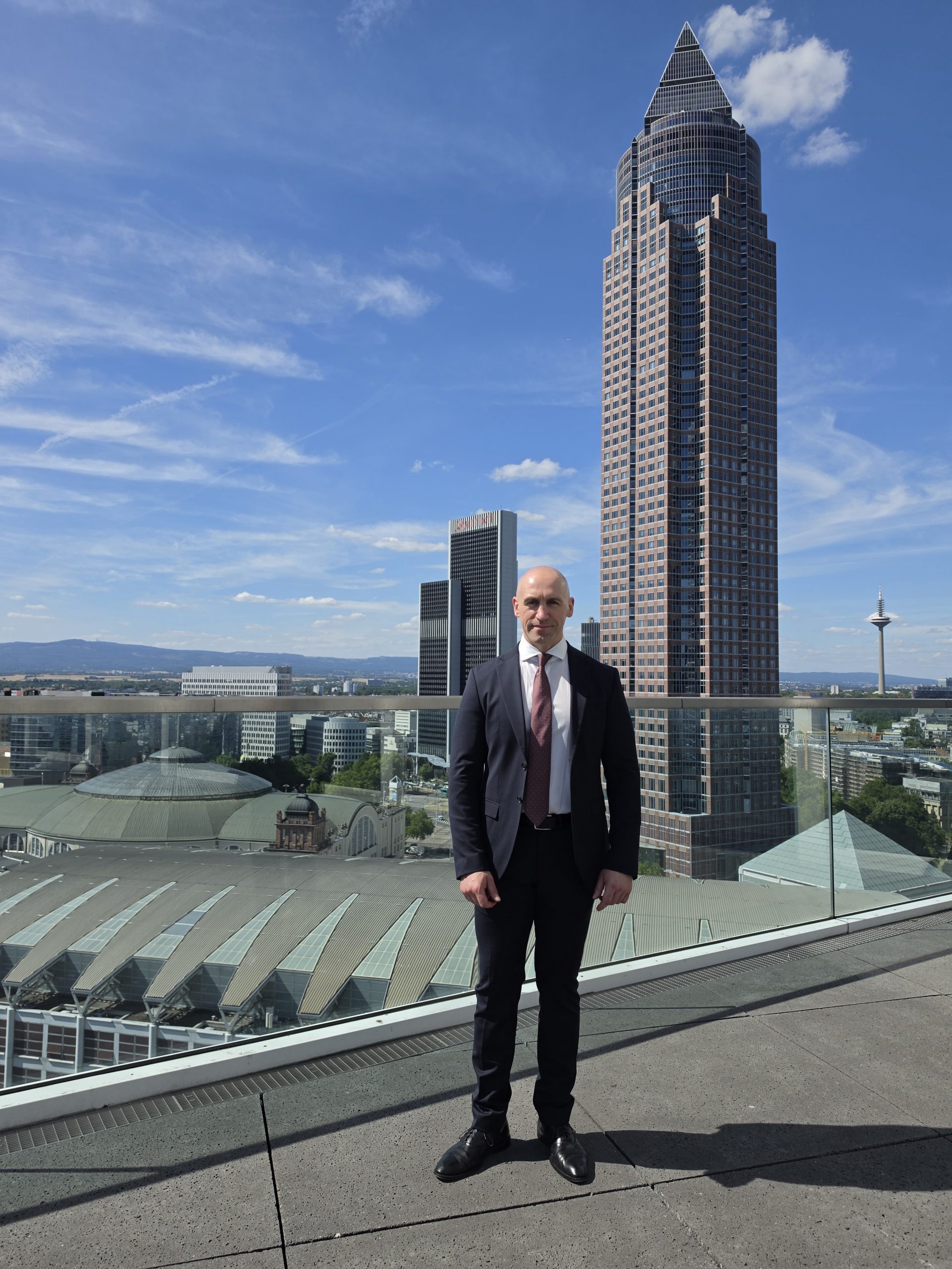 Ronny Kazyska auf einer Hochhausterrasse in Frankfurt am Main mit Messeturm und Skyline im Hintergrund zum Grundsatz Verantwortung in der Immobilienbewertung.