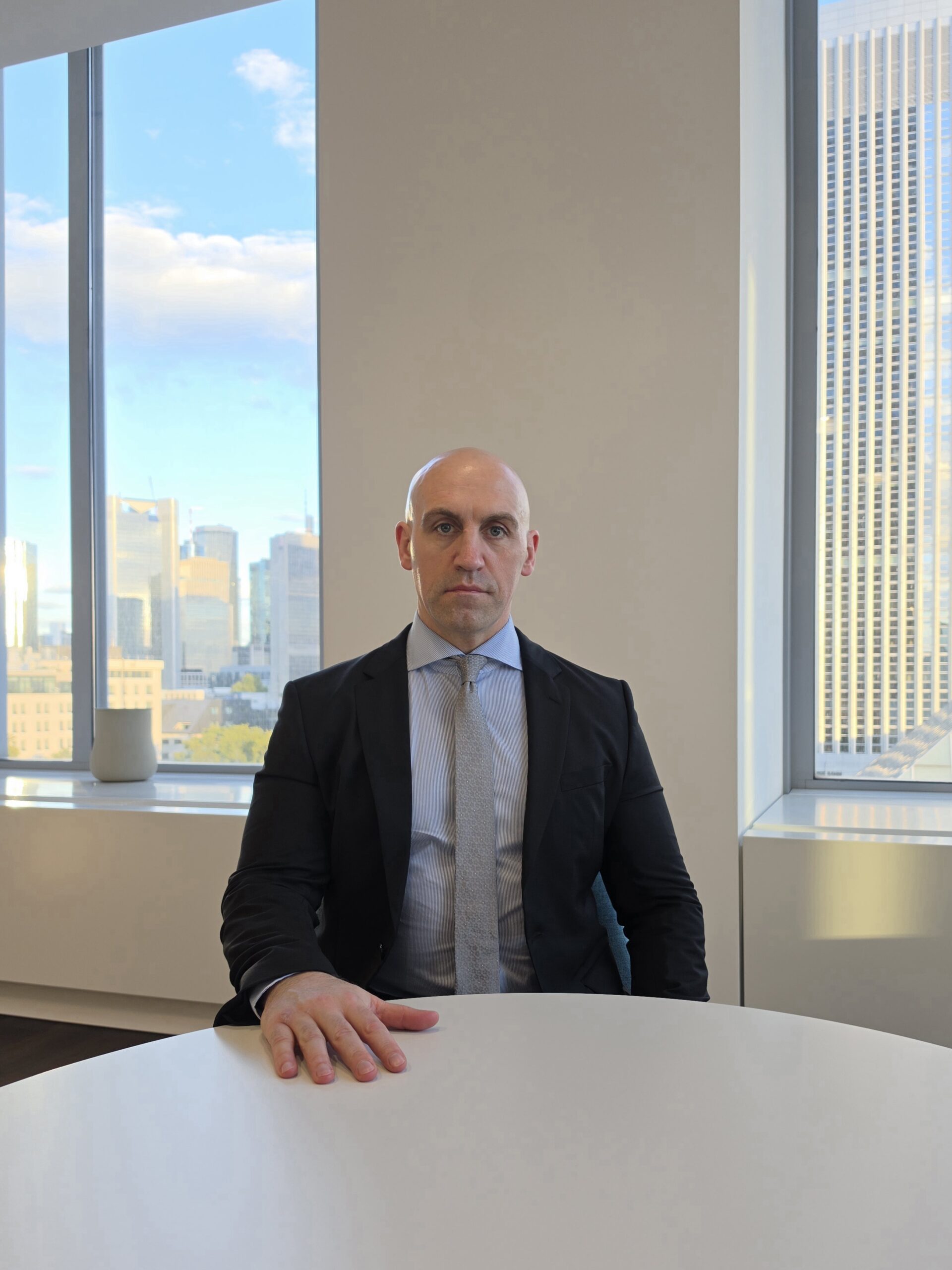 Ronny Kazyska im Büro im Frankfurter Messeturm mit Blick auf die Frankfurter Skyline.